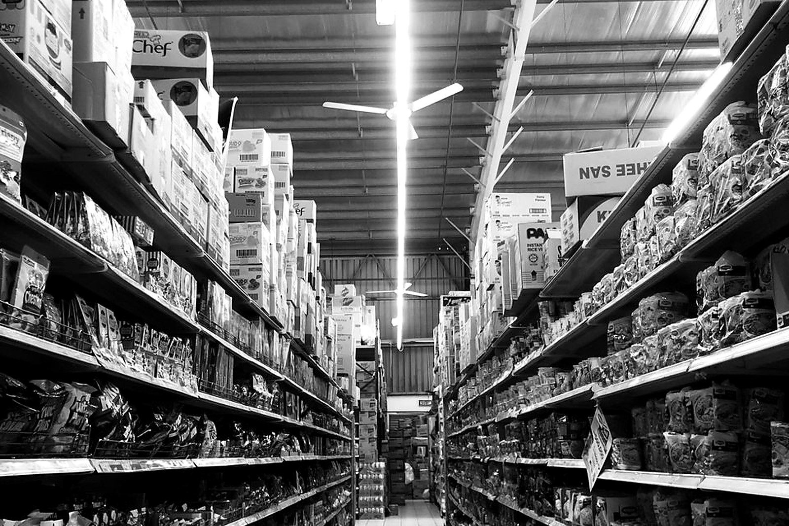 Free Black and white of shelves with different food and boxes placed in rows in shop with bright illumination Stock Photo